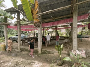 A group of local community members talking and gathering inside the newly constructed open-air mission church structure.