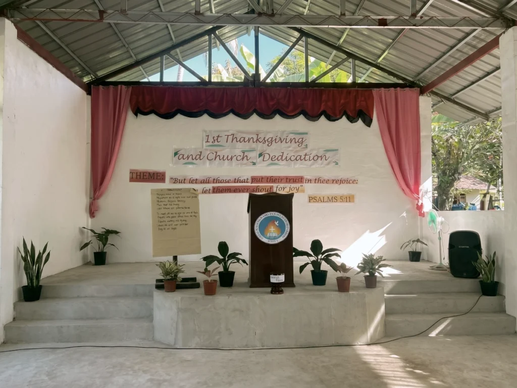 A symmetrical view of the decorated altar and wooden pulpit inside a newly dedicated open-air mission church.