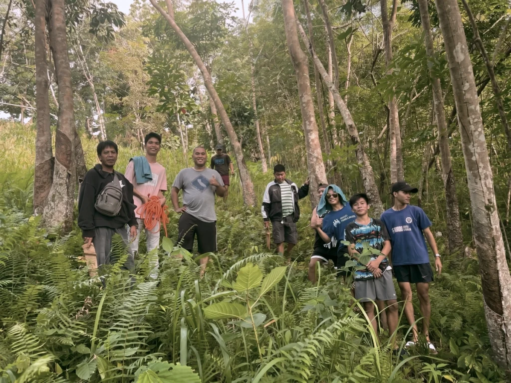 A local mission team standing together on a forested hill while preparing or scouting land for a church planting project.