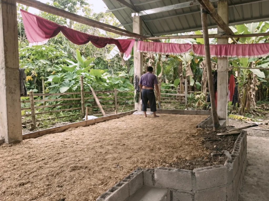 A worker preparing the dirt floor foundation inside an open-air church building structure under construction.