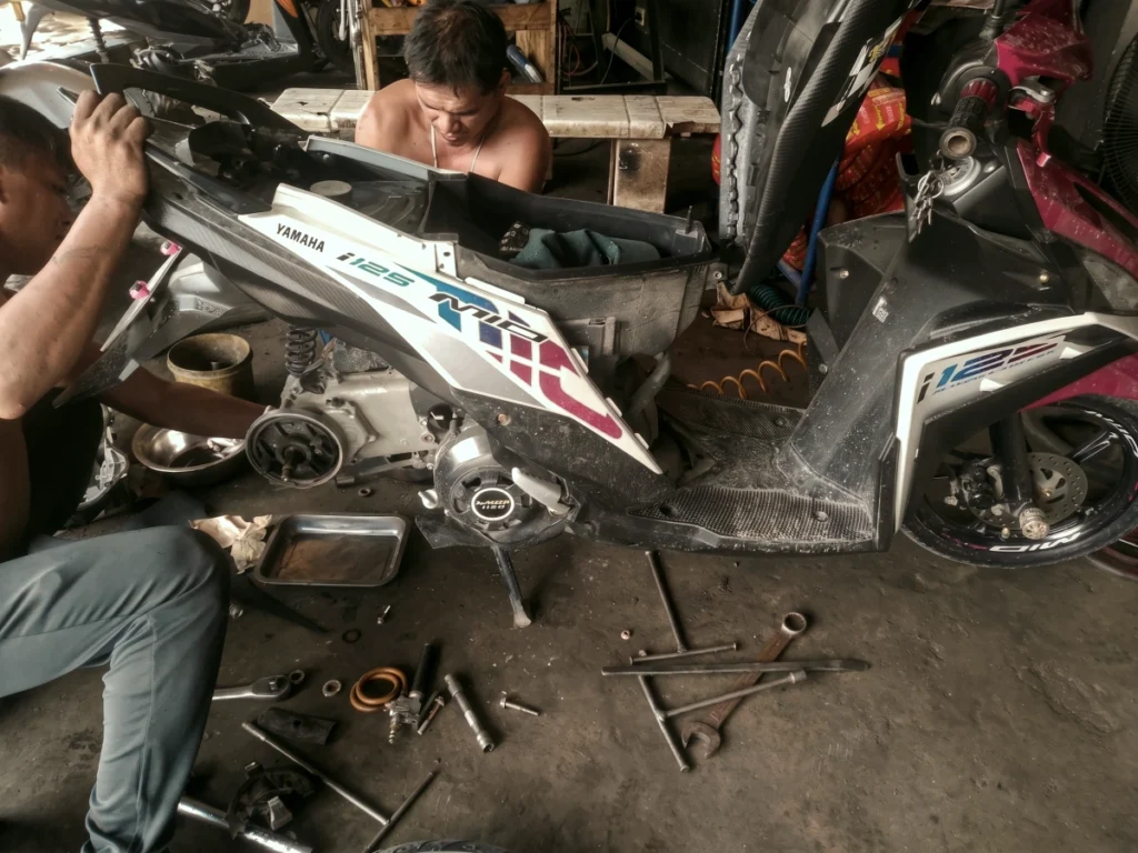 Two men working hard in a local garage to fix up a donated scooter, preparing the vehicle to give the gift of mobility to a local family.